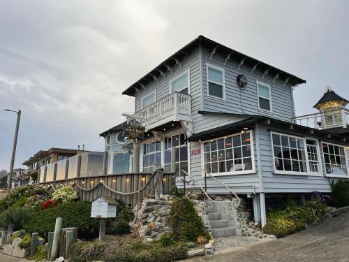 A charming coastal restaurant with a wooden exterior, surrounded by greenery and a cloudy sky.
