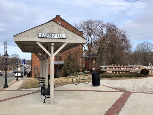 A small shelter labeled "Farmville" near a park entrance, with a bike and trash can nearby.