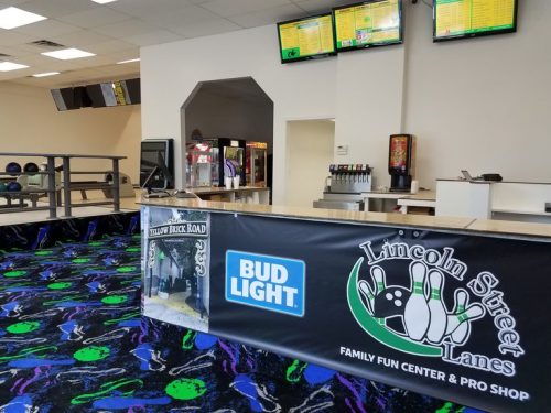 Interior of Lincoln Street Lanes featuring a snack bar, arcade games, and colorful bowling alley carpet.