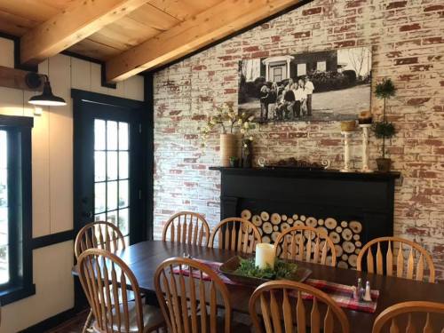 Cozy dining area with a wooden table, rustic chairs, and a brick wall featuring a vintage photo and decorative elements.