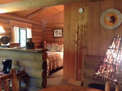 Cozy log cabin interior featuring a bedroom, wooden furniture, and warm lighting.