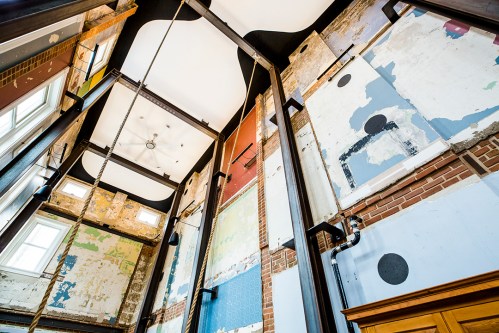 Interior view of a building with exposed brick and colorful, peeling paint on the walls, showcasing industrial architecture.
