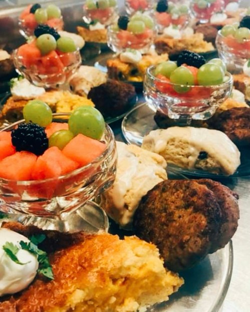 A platter of desserts featuring fruit cups, cornbread, and pastries, beautifully arranged on silver trays.