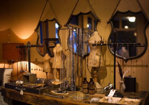 A display of elegant jewelry on mannequins and stands, with mirrors reflecting warm ambient lighting.