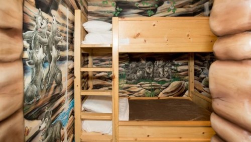 Bunk beds in a room with mural of wolves and a natural landscape on the walls, creating a cozy, rustic atmosphere.