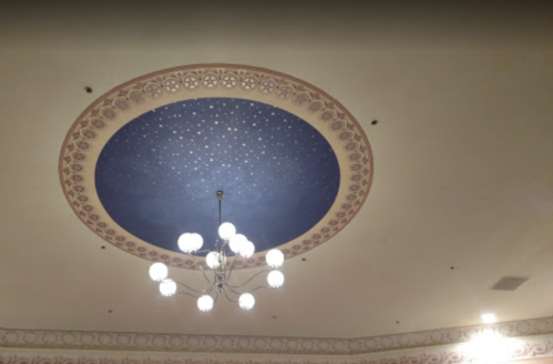 A decorative ceiling featuring a blue circular design with stars and a chandelier below.