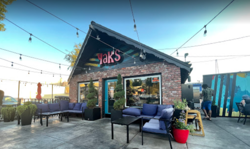 A cozy restaurant named "Yak's" with outdoor seating, string lights, and a vibrant atmosphere.