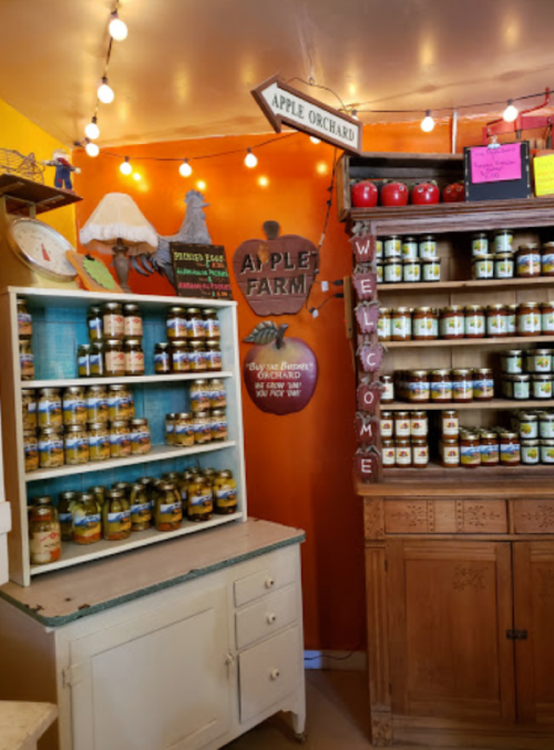 A cozy shop interior with shelves of jars, an "Apple Orchard" sign, and warm lighting creating a welcoming atmosphere.