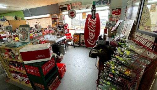 A vintage store filled with Coca-Cola memorabilia, bottles, and coolers, showcasing a nostalgic atmosphere.