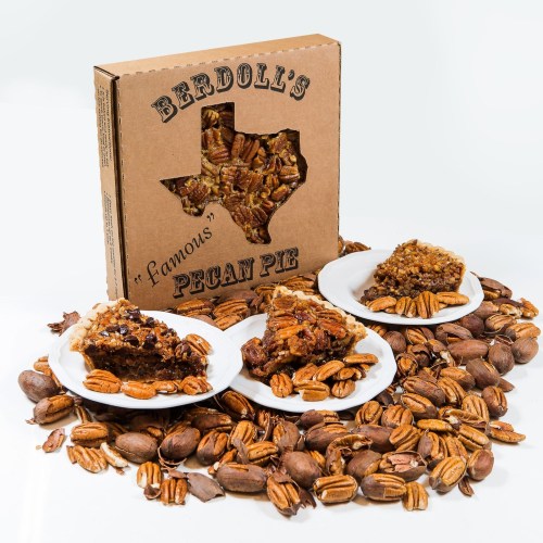 A box of Berdoll's famous pecan pie surrounded by whole pecans and slices of pie on white plates.