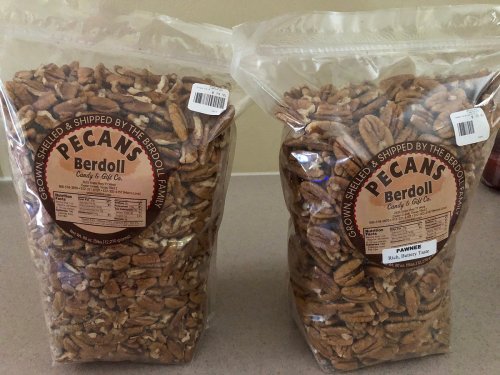 Two clear bags of shelled pecans labeled "Berdoll" on a countertop, showcasing the nuts inside.