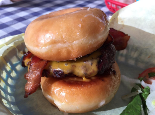 A stacked burger with a cheeseburger patty and bacon, served between two glazed donut halves.