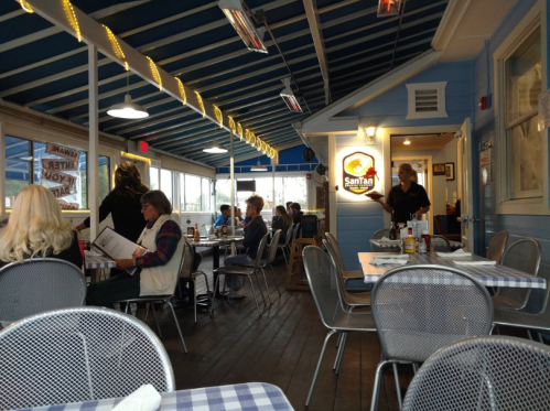 A cozy restaurant interior with blue walls, diners at tables, and a server attending to guests.