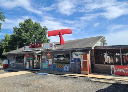 A rustic building with a red airplane on the roof, featuring vintage signs and a welcoming entrance.