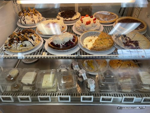 A display case filled with various desserts, including pies, cakes, and whipped cream-topped treats.