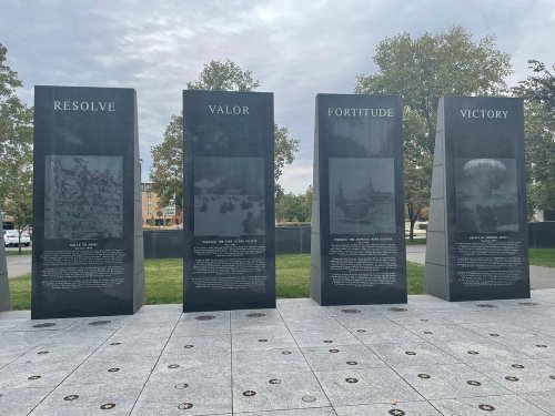 Four stone monuments with inscriptions: "Resolve," "Valor," "Fortitude," and "Victory," set in a grassy area.