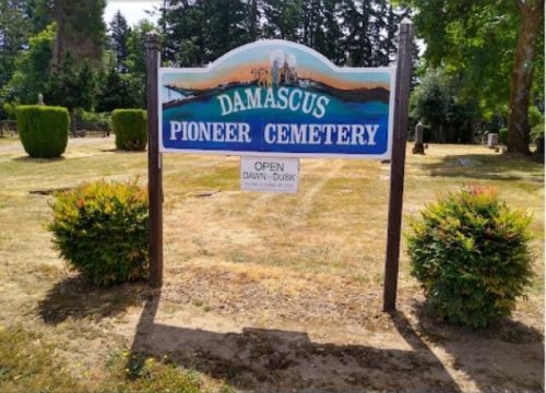 Sign for Damascus Pioneer Cemetery, featuring greenery and trees, with hours listed as open from dawn to dusk.
