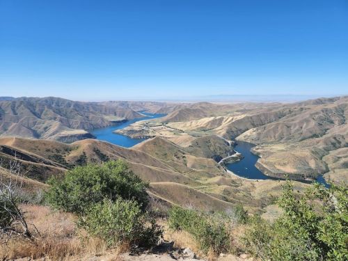 A panoramic view of rolling hills and a winding river under a clear blue sky.