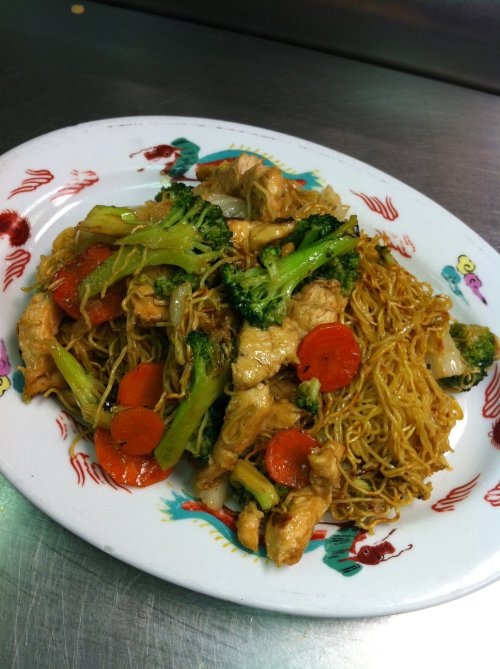 A plate of stir-fried noodles with chicken, broccoli, and carrots, garnished with colorful patterns.
