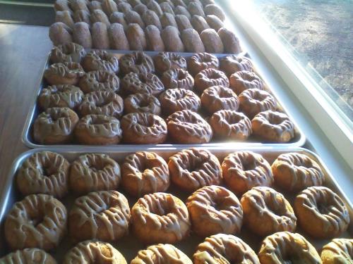 Trays of freshly baked pastries, including glazed donuts and cinnamon rolls, arranged neatly on a table.