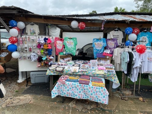 A colorful market stall displaying various handmade items, including clothing, accessories, and decorations.