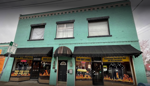 A turquoise building with a black awning, featuring windows and signage for "Big Bay's Ribs" and "Lil' 2 Brothers."