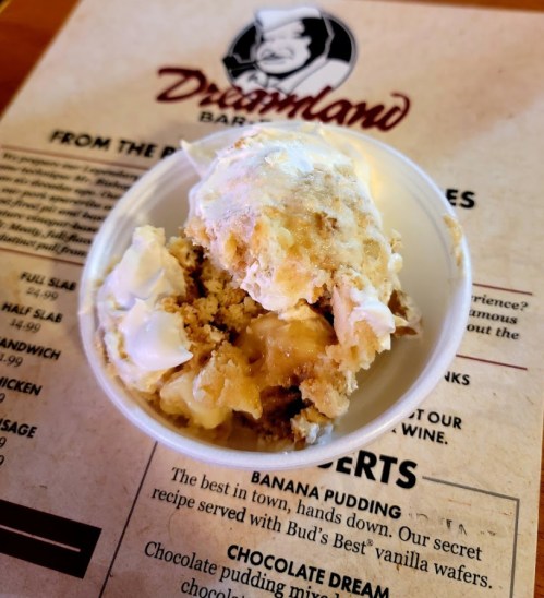 A bowl of banana pudding topped with whipped cream, placed on a menu background.