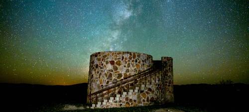 A stone structure under a starry night sky, with the Milky Way visible above.