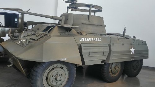 A military armored vehicle with a star insignia, displayed indoors, featuring a turret and large wheels.