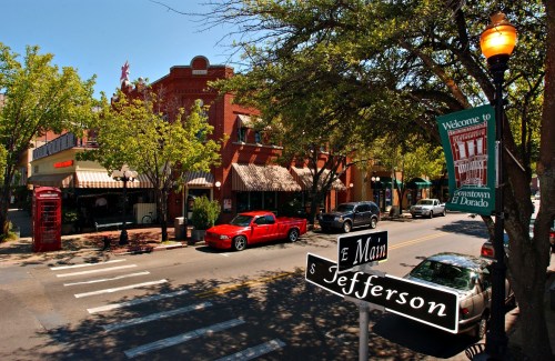 A vibrant downtown scene with shops, trees, and street signs at the intersection of Main and Jefferson.