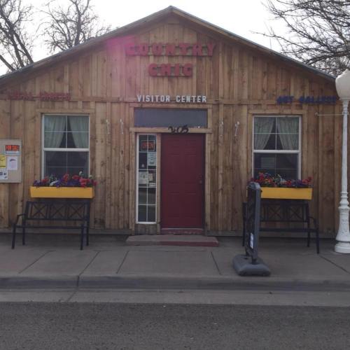 A wooden building with a sign reading "Country Gift Visitor Center," featuring flower boxes and a welcoming entrance.