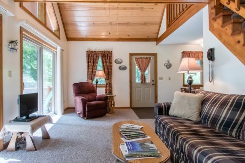 Cozy living room with a plaid sofa, recliner, coffee table, and large windows letting in natural light.