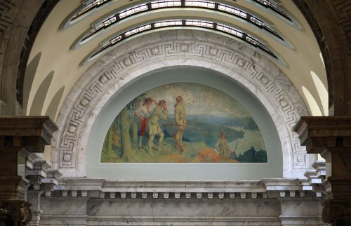Mural depicting figures in a landscape, set in an arched architectural space with decorative stonework.