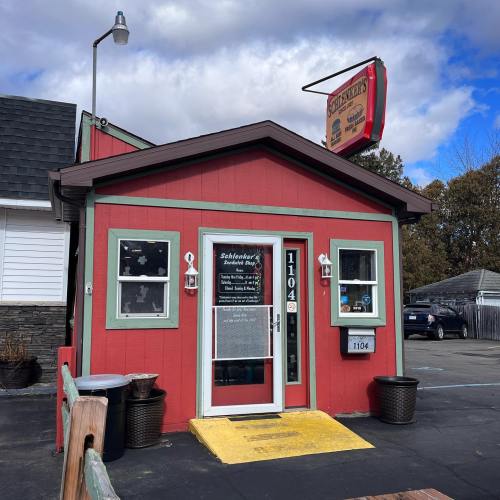 A small red building with green trim, featuring a sign for "Scholz's" and a welcoming entrance.