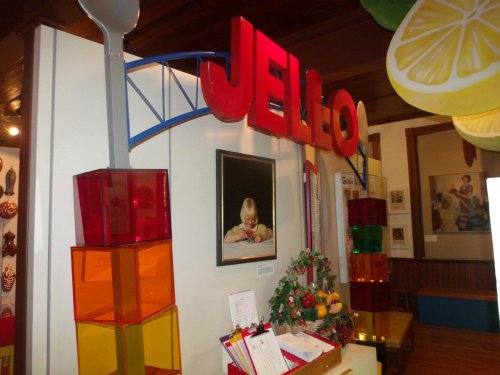 Colorful display featuring a large "JELL-O" sign, stacked gelatin cubes, and a child looking at a dessert.