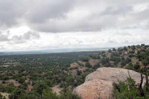 A panoramic view of a green landscape with rocky outcrops under a cloudy sky.