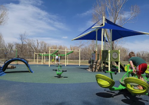A colorful playground with green equipment, a blue shade structure, and children playing under a clear blue sky.