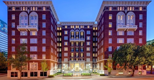 Historic brick building with elegant architecture, featuring large windows and a welcoming entrance, illuminated at dusk.