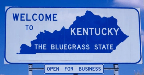 Welcome sign for Kentucky, featuring the state outline and the phrase "The Bluegrass State." Open for business.