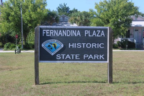 Sign for Fernandina Plaza Historic State Park, featuring the Florida Park Service logo, set in a grassy area.