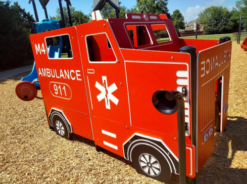 A colorful playground structure designed like an ambulance, featuring a 911 emblem and playful details.