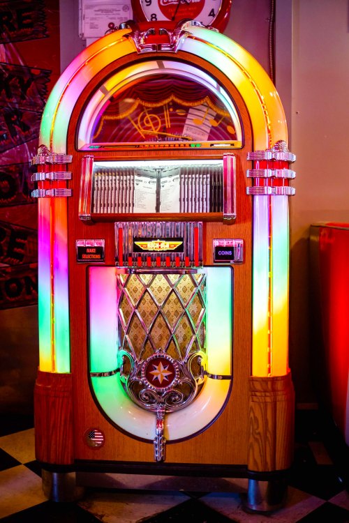 A colorful vintage jukebox with neon lights, featuring a classic design and a shiny chrome front.