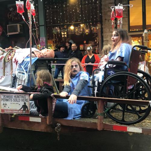 A spooky scene with people in wheelchairs dressed as zombies, surrounded by fake blood and Halloween decorations.