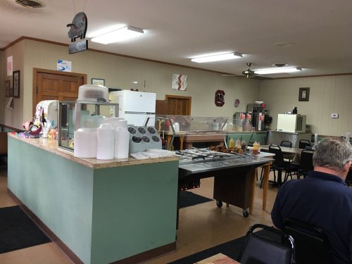 A cozy diner interior with a serving counter, tables, and a variety of condiments displayed.