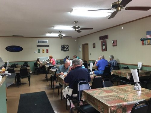 A casual dining area with tables and chairs, featuring patrons enjoying meals in a cozy, relaxed atmosphere.
