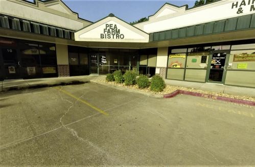 Exterior of a shopping plaza featuring "Pea Farm Bistro" with nearby businesses and a parking lot.