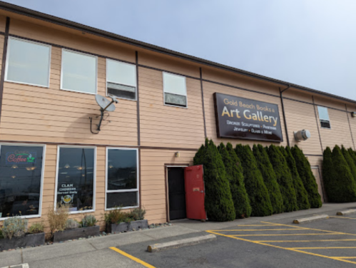 Exterior of Gold Beach Books Art Gallery, featuring a sign, windows, and neatly trimmed hedges.