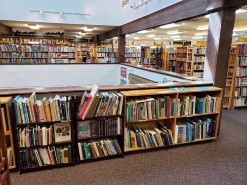 A spacious bookstore with shelves filled with books, featuring multiple levels and a cozy reading area.