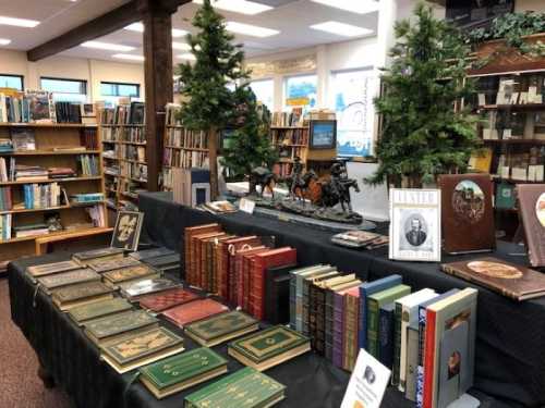 A library display featuring vintage books, decorative trees, and a statue, set on a black tablecloth.