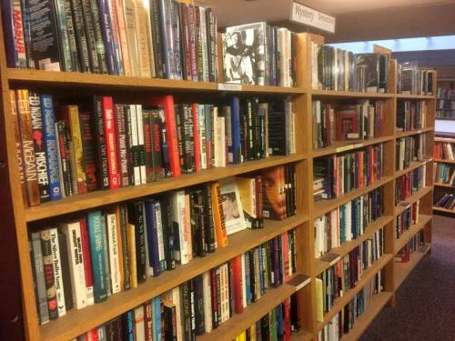 Bookshelves filled with various mystery novels in a library setting.